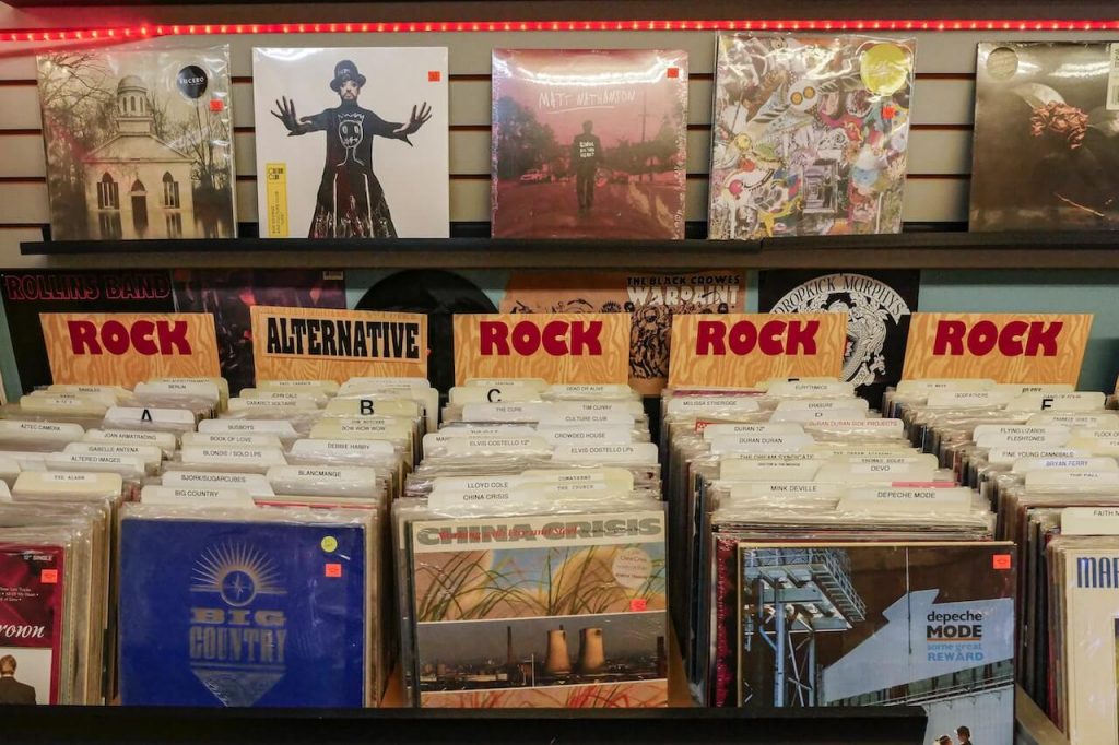 Immagine di un negozio di musica con file di dischi rock, con una variegata collezione di album rock.